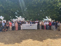 A group of people standing in a field showing a Banner with "PROTECHMED" written on it.